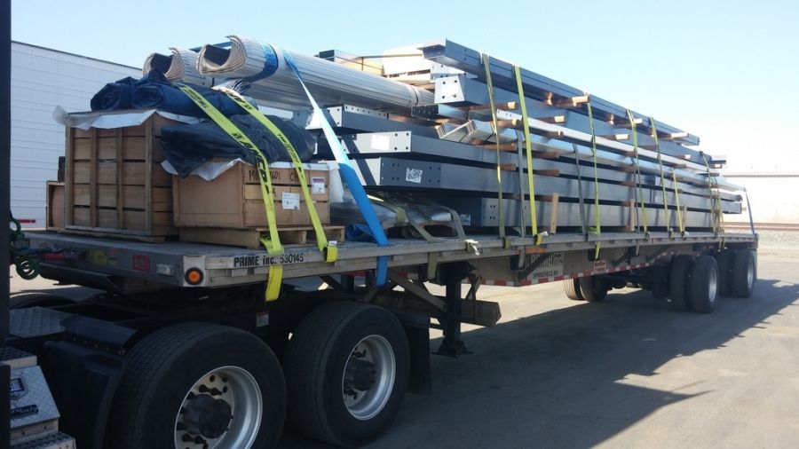 a steel building in pieces strapped to a flatbed trailer