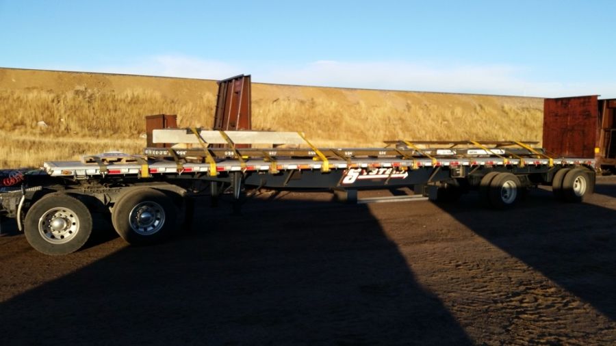 LTL flatbed trailer loaded and strapped with railroad ties and steel rails
