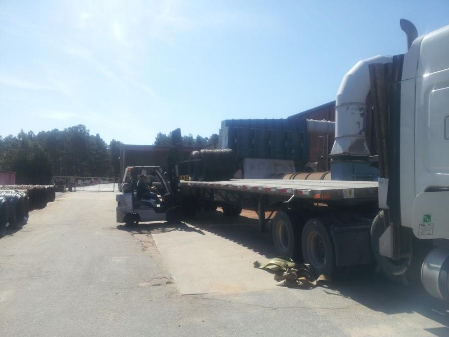 forklift loading metal slinky coils on flatbed trailer