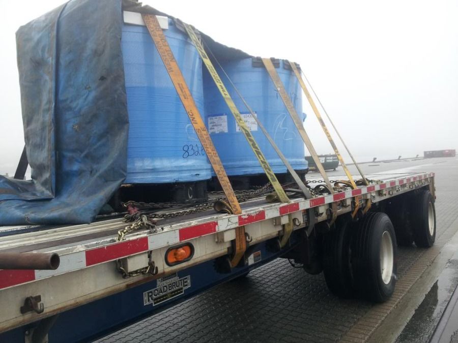steel coils loaded and strapped on flatbed upright eye to the sky covered with tarp