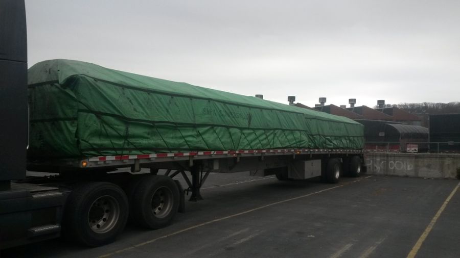 long joints of aluminum extrusions loaded and strapped and tarped on SAPA flatbed trailer in the warehouse