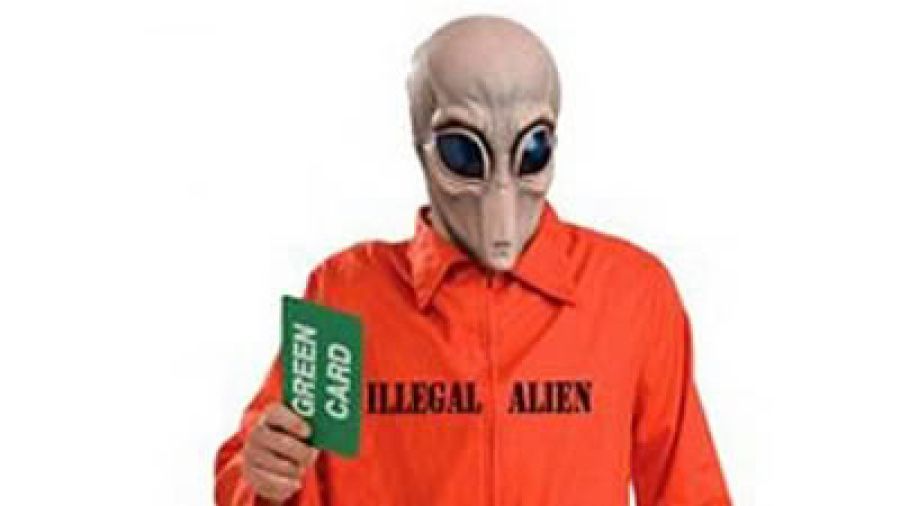 Illegal space alien holding green card in an orange jump suit