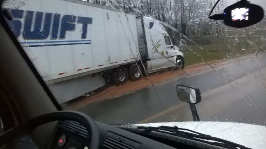 Swift truck parked in the mud and rain with trailer sticking out in the road