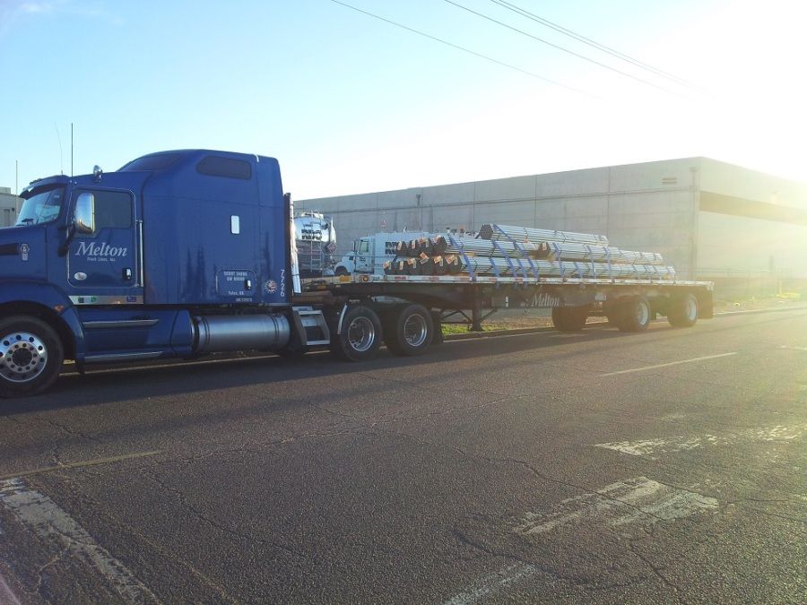 Melton flatbed loaded with steel bars strapped and tarped