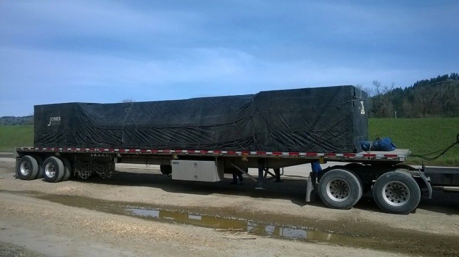 load of plywood strapped and tarped on flatbed trailer
