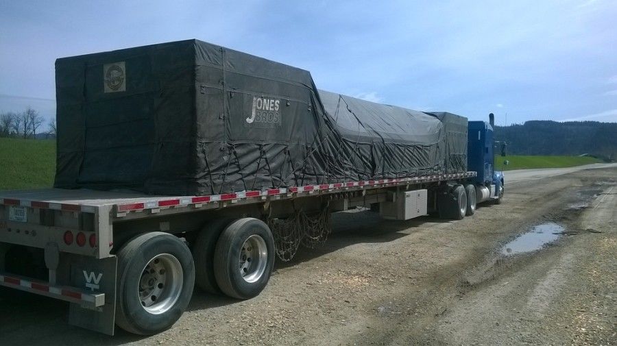 load of plywood strapped and tarped on flatbed trailer