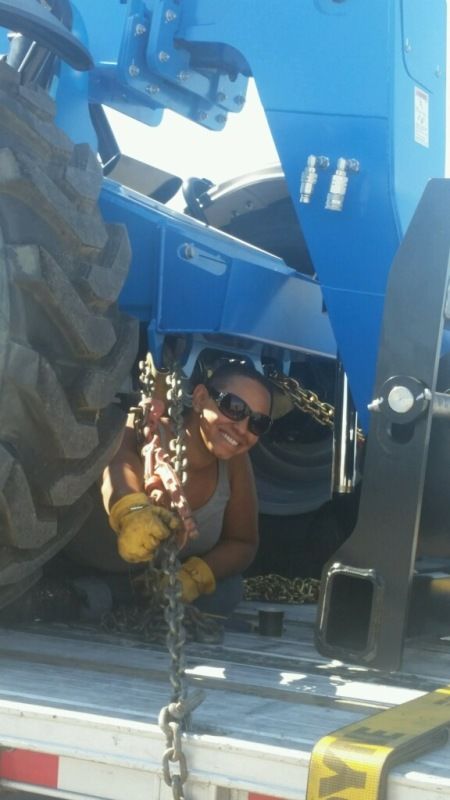 female truck driver chaining a tractor to flatbed trailer