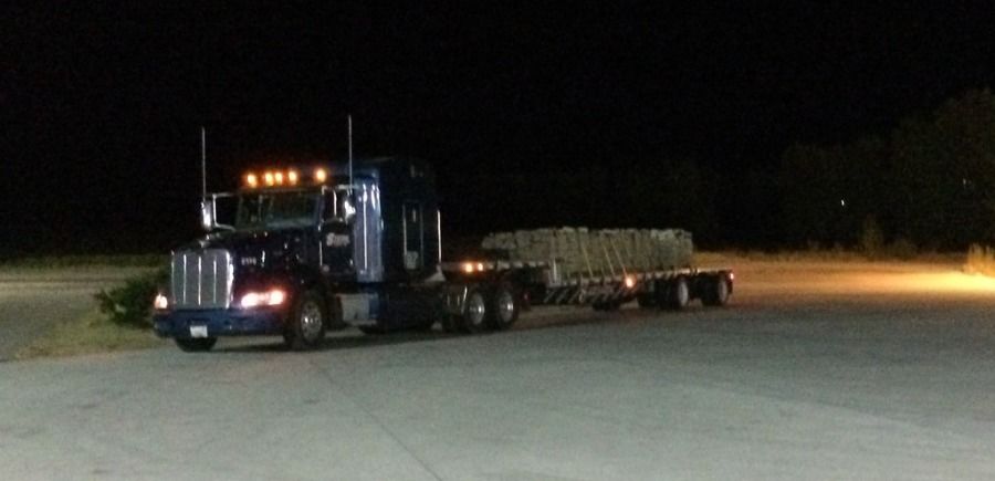 blue system truck pulling flatbed trailer loaded with decorative stone