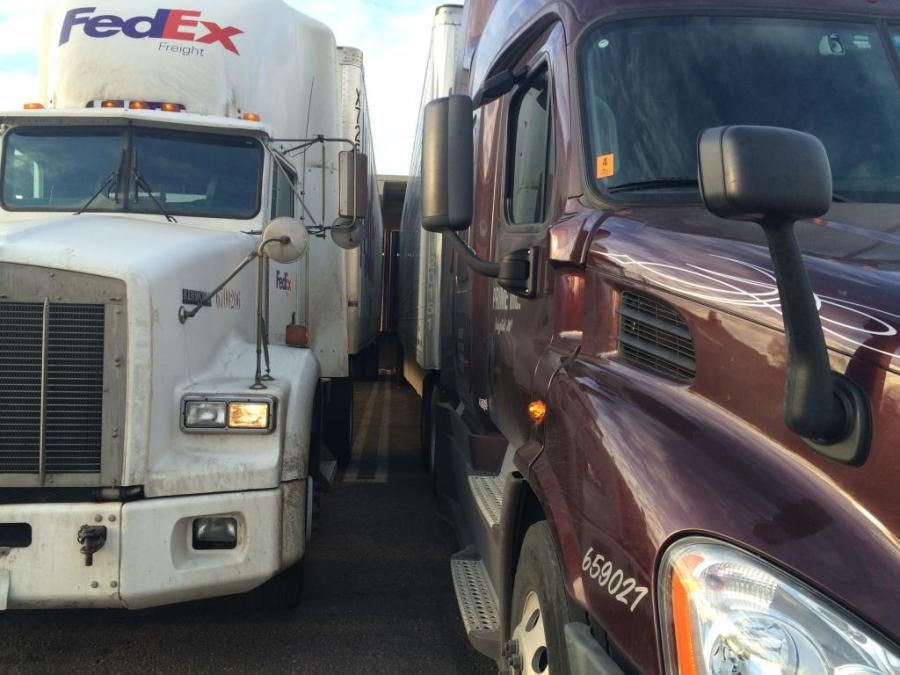 tractor trailer parked very close to a fedex truck