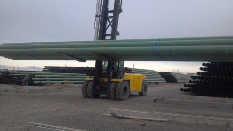 large forklift loading pipe on a flatbed trailer
