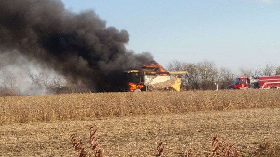 farm combine on fire in wheat field