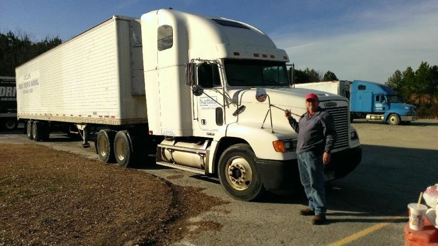 truck driver standing in front of his truck at truck driving school