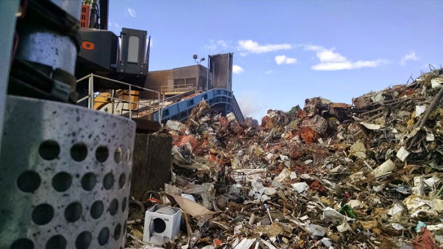 A scrap metal pile at a recycling plant, the belt that feeds the shredder, and part of the Barko that unloads the trucks and feeds the shredder.