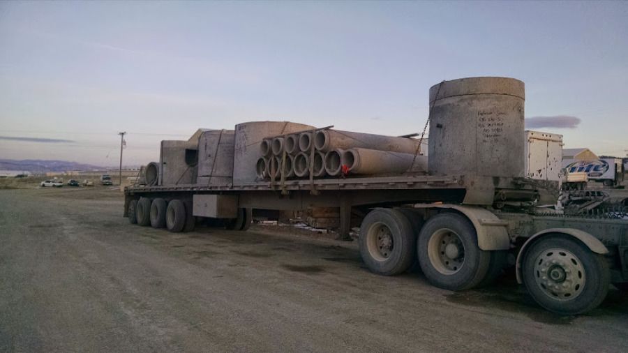 long flatbed trailer loaded with cement pipes and chained
