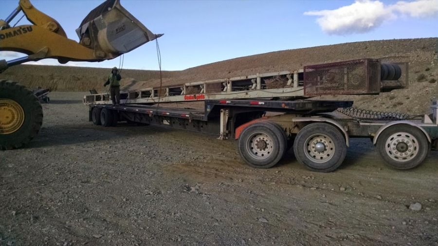 heavy loader unloading a rockscreen from flatbed trailer