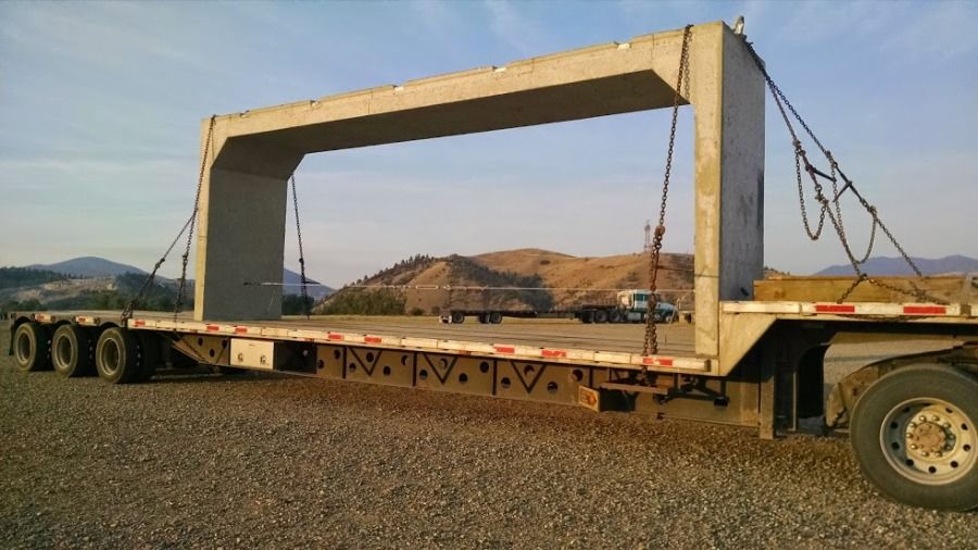 flatbed loaded with large cement bridge piece