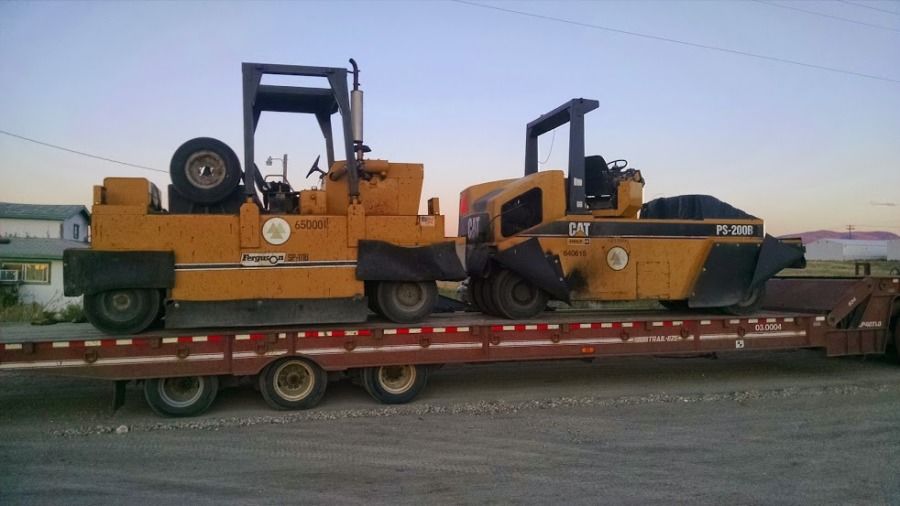two caterpillar rollers loaded on a flatbed trailer