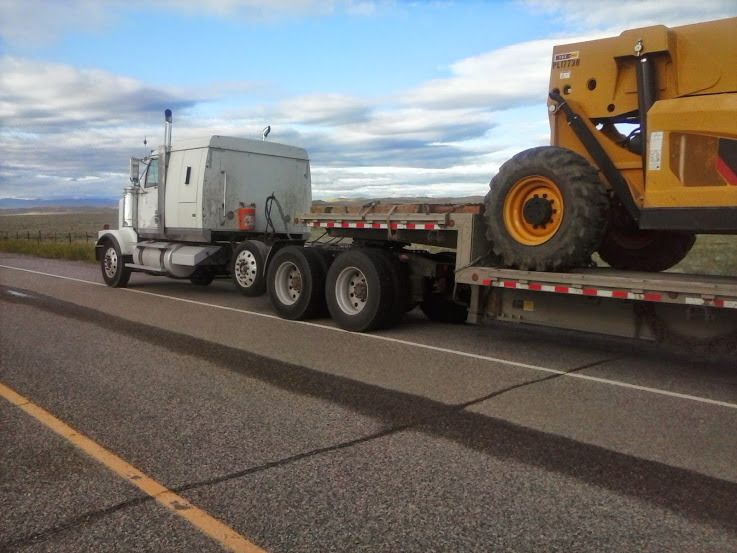 truck pulling flatbed trailer carrying heavy equipment