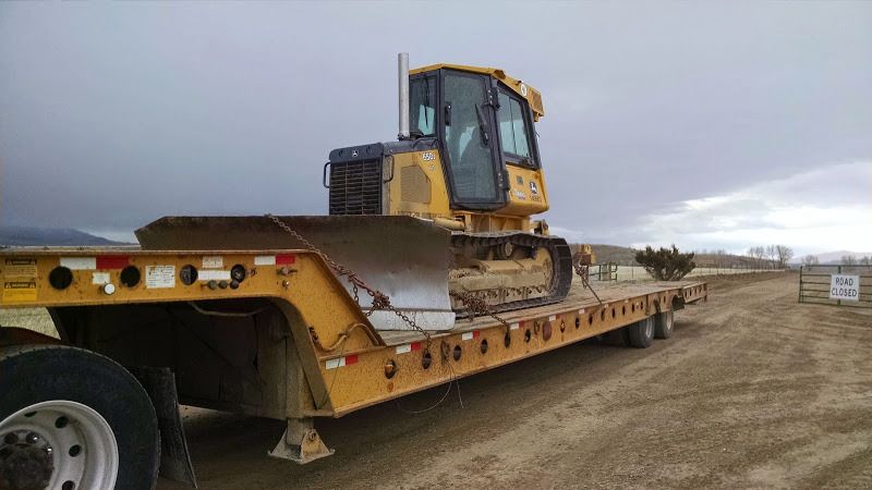 bulldozer loaded on yellow flatbed drop-deck trailer