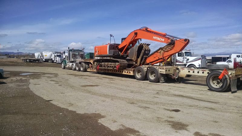 dropdeck flatbed trailer loaded with orange Hitachi backhoe excavator
