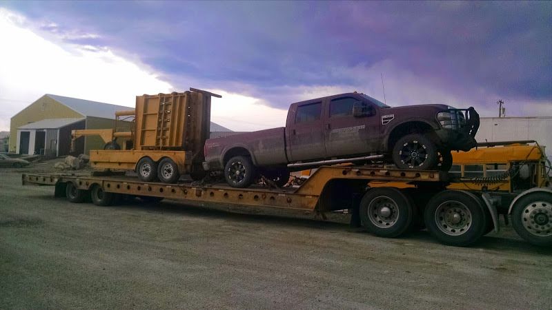 pickup truck and construction equipment loaded on flatbed trailer