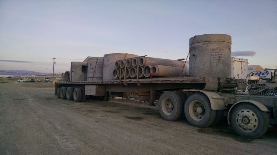 flatbed trailer loaded with various sizes of cement pipe using v-boards