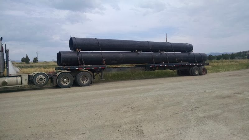 flatbed trailer loaded and strapped with large long steel water pipe