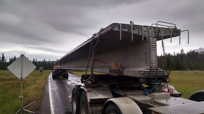 flatbed trailers with dollies carrying giant cement bridge beams