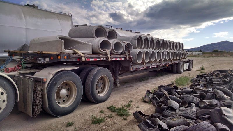 flatbed trailer loaded with large cement pipes