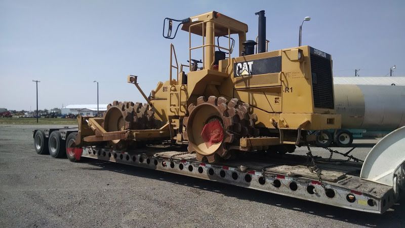 Extra-wide CAT excavator loaded and chained on flatbed trailer