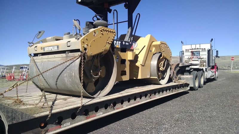 small CAT steamroller chained to flatbed trailer