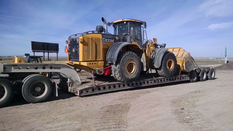 John Deere 824 loader chained onto a flatbed trailer