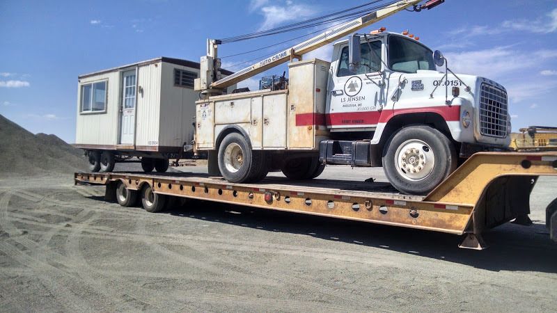 telecomm boom truck and office trailer loaded on flatbed trailer