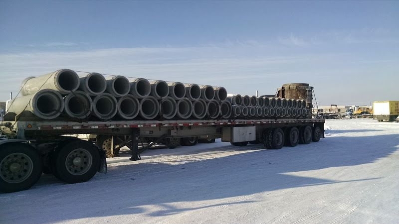 concrete pipes loaded and chained eyes crosswise on flatbed trailer in winter snow