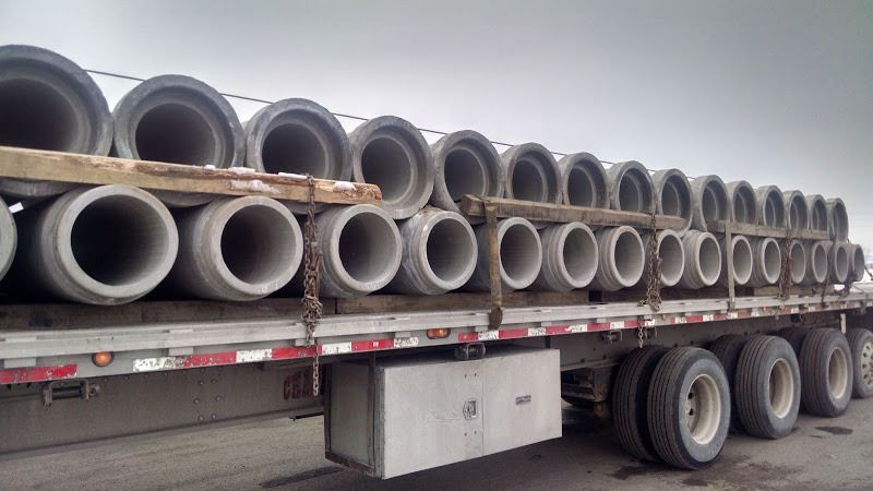 cement bell-end pipe loaded and secured on a flatbed trailer with dunnage